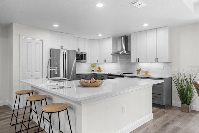 3416 Lema Dr, Spring Hill, FL 34609 - kitchen featuring wall chimney range hood, visible vents, light wood-style floors, and stainless steel appliances