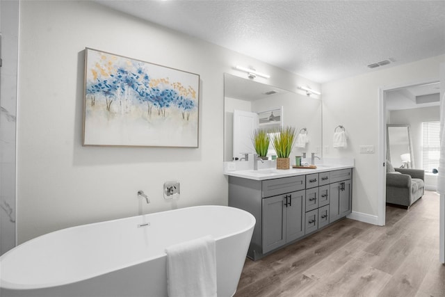 3416 Lema Dr, Spring Hill, FL 34609 - ensuite bathroom with a freestanding tub, a sink, wood finished floors, visible vents, and double vanity