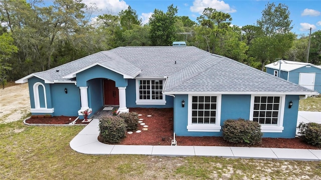 view of front of home featuring a shingled roof, stucco siding, and a front lawn