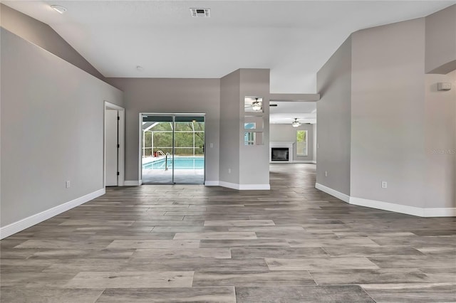 empty room featuring a ceiling fan, vaulted ceiling, wood finished floors, and baseboards