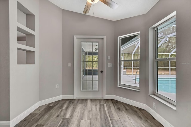 doorway to outside featuring wood finished floors, plenty of natural light, ceiling fan, and baseboards