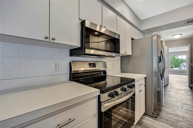 kitchen featuring stainless steel appliances, light countertops, tasteful backsplash, light wood finished floors, and white cabinets