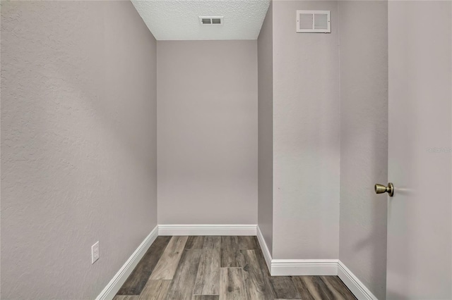 interior space with wood finished floors, baseboards, and a textured ceiling