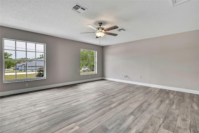 spare room with wood finished floors, a ceiling fan, a textured ceiling, and baseboards