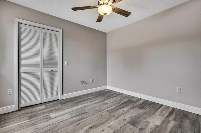 unfurnished room with wood finished floors, ceiling fan, baseboards, and a textured ceiling
