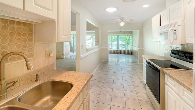 kitchen with light tile patterned flooring, a sink, electric stove, ceiling fan, and white microwave