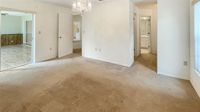 unfurnished bedroom with an inviting chandelier, carpet floors, and baseboards