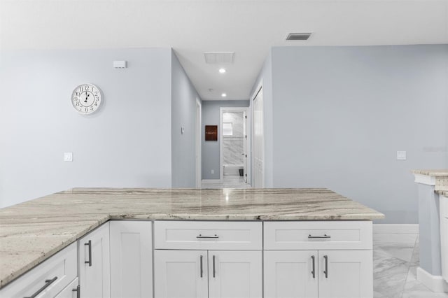 kitchen featuring marble finish floor, light stone countertops, visible vents, and white cabinets