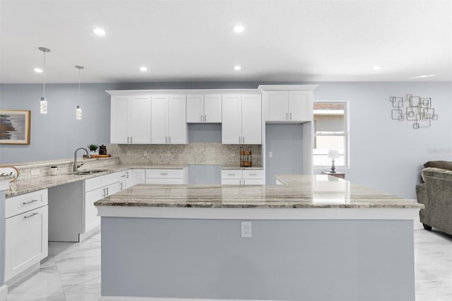 kitchen featuring marble finish floor, backsplash, a center island, and a sink