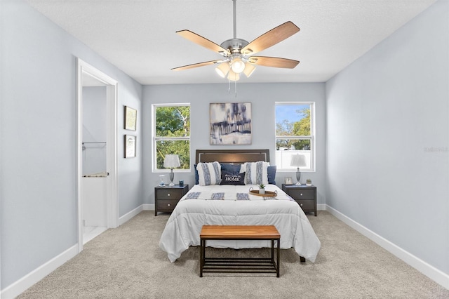 carpeted bedroom with baseboards, a textured ceiling, multiple windows, and a ceiling fan
