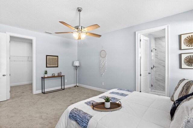 carpeted bedroom featuring ensuite bathroom, a closet, visible vents, baseboards, and a spacious closet