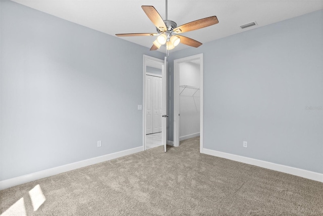 spare room featuring carpet floors, baseboards, visible vents, and ceiling fan