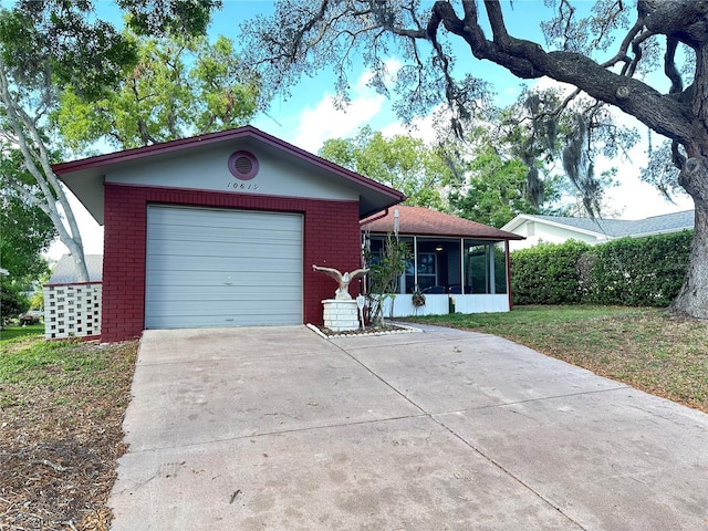 ranch-style home with driveway, an attached garage, brick siding, a front lawn, and a sunroom