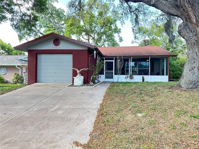 ranch-style house featuring a sunroom, an attached garage, concrete driveway, a front yard, and brick siding