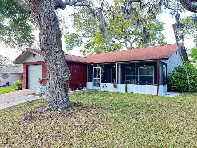 single story home featuring a front yard, concrete driveway, a shingled roof, a sunroom, and a garage