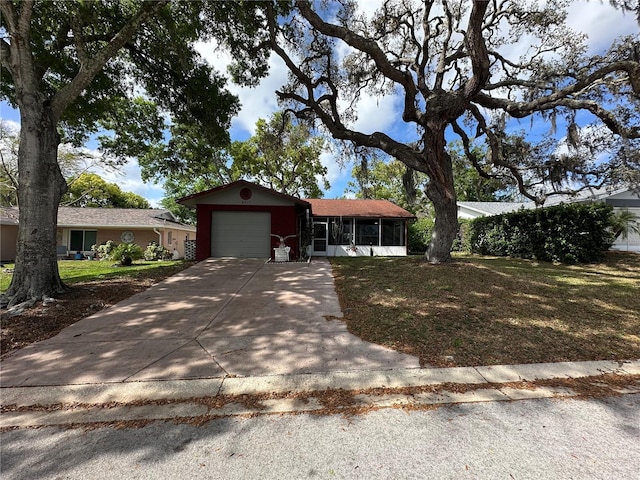 single story home featuring a front yard, a sunroom, a garage, and concrete driveway