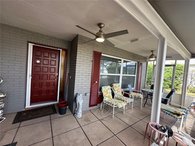 entrance to property with covered porch, a ceiling fan, and brick siding