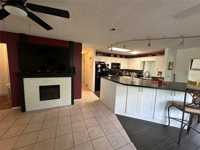 kitchen with a ceiling fan, dark countertops, black appliances, and white cabinets
