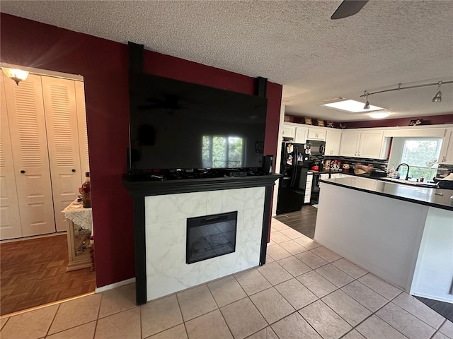 kitchen featuring white cabinetry, dark countertops, black appliances, and a textured ceiling