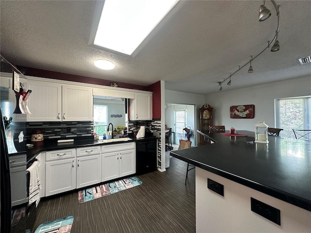 kitchen featuring white cabinets, a sink, dark countertops, and tasteful backsplash