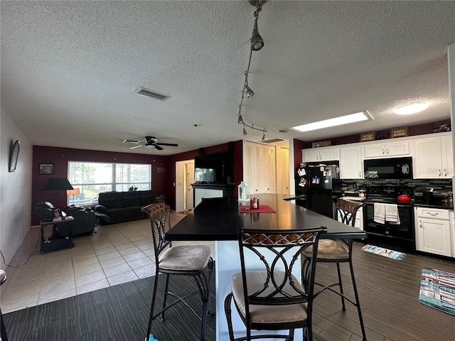 kitchen featuring visible vents, dark countertops, tasteful backsplash, white cabinetry, and black appliances