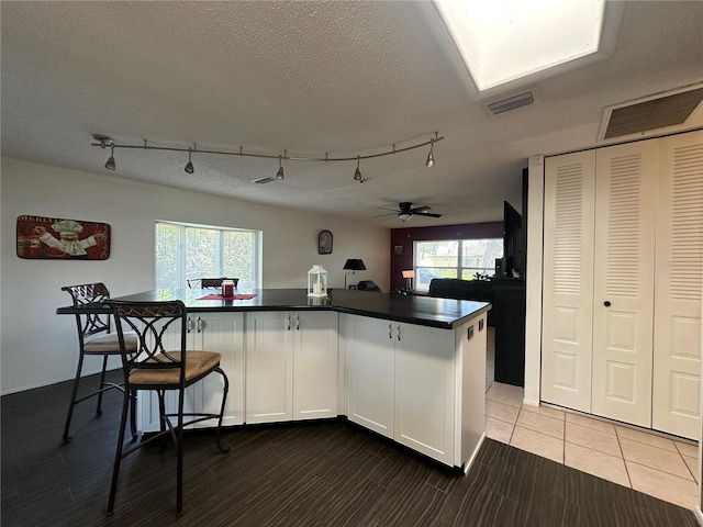 kitchen with a healthy amount of sunlight, a textured ceiling, visible vents, and dark countertops