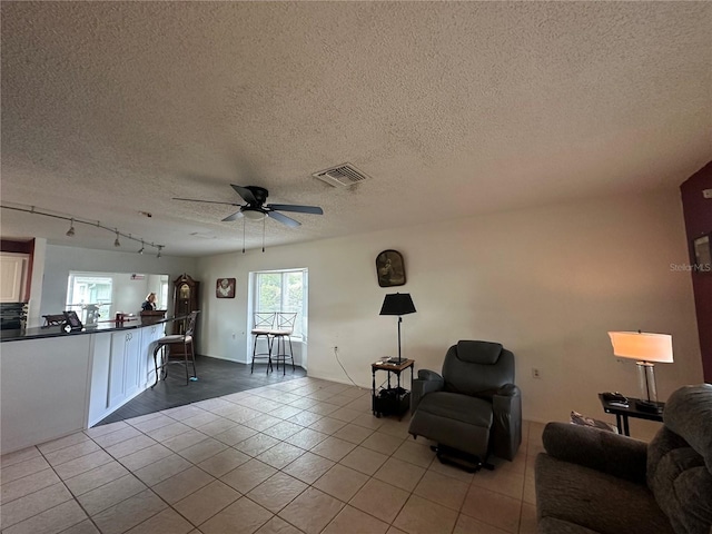 unfurnished living room featuring a textured ceiling, visible vents, track lighting, ceiling fan, and tile patterned flooring