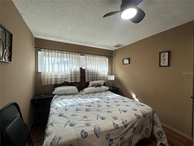 bedroom featuring baseboards, a textured ceiling, ceiling fan, visible vents, and wood finished floors