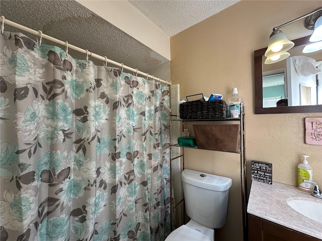 bathroom featuring vanity, toilet, a textured wall, a shower with shower curtain, and a textured ceiling