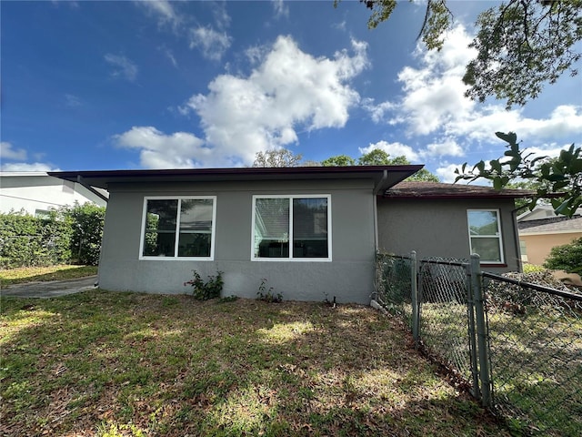 view of side of home featuring a lawn, stucco siding, and fence