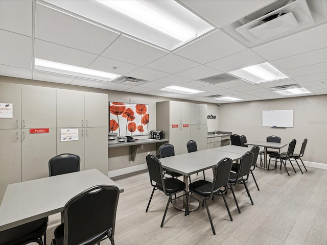 dining area with baseboards, visible vents, a paneled ceiling, and light wood-type flooring