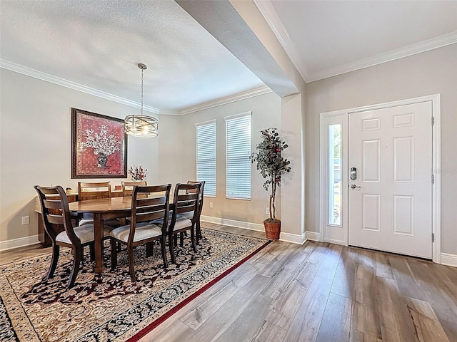 dining area with baseboards, wood finished floors, a chandelier, and crown molding