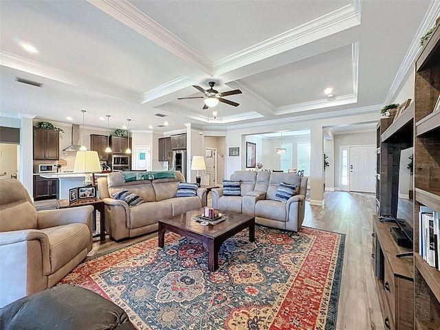 living room featuring coffered ceiling, crown molding, light wood finished floors, visible vents, and ceiling fan