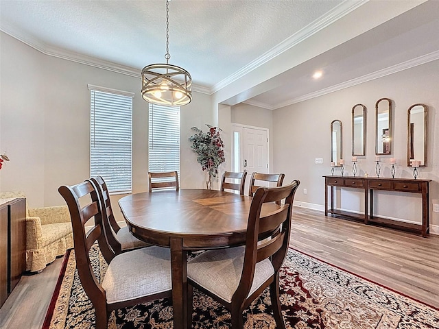 dining area with baseboards, light wood-style flooring, a chandelier, and crown molding
