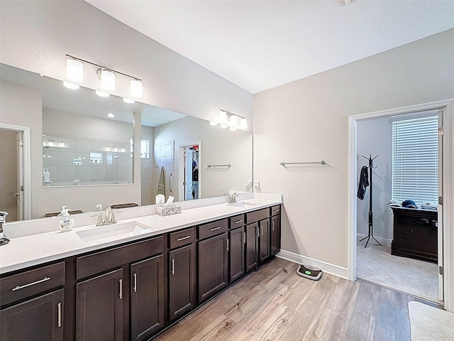 bathroom featuring tiled shower, a sink, baseboards, and wood finished floors