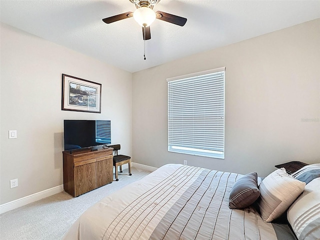 bedroom featuring light colored carpet, baseboards, and a ceiling fan