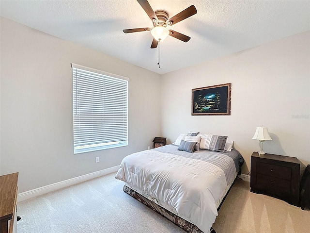bedroom featuring baseboards, ceiling fan, carpet, and a textured ceiling