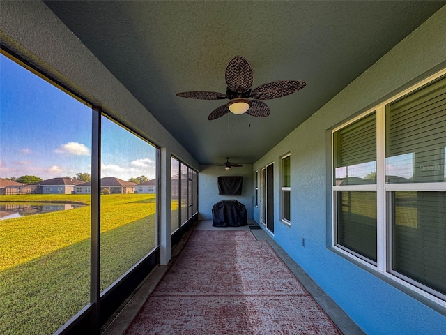 unfurnished sunroom with a water view and ceiling fan