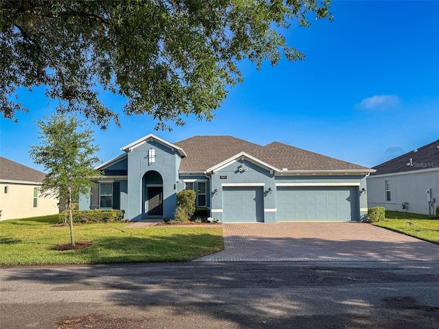ranch-style home with driveway, stucco siding, an attached garage, and a front lawn