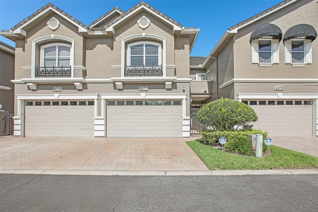 view of front of house with stucco siding, decorative driveway, and a garage