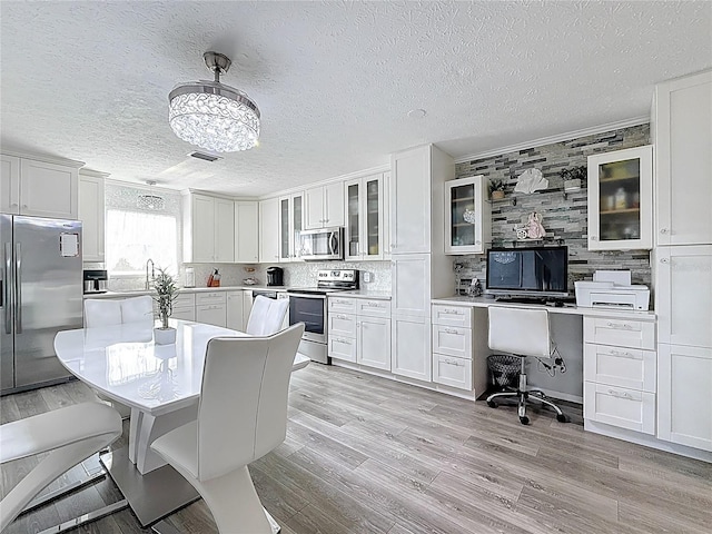 7382 SE Concord Pl, Hobe Sound, FL 33455 - dining area featuring crown molding, a textured ceiling, an inviting chandelier, and light wood finished floors