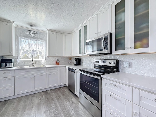 7382 SE Concord Pl, Hobe Sound, FL 33455 - kitchen featuring appliances with stainless steel finishes, a sink, light countertops, a textured ceiling, and tasteful backsplash