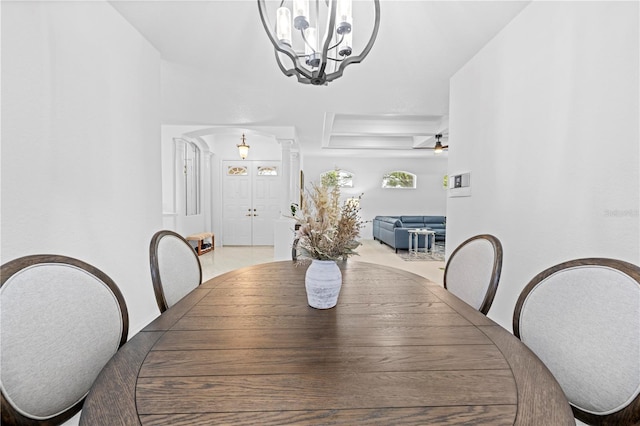 dining room with ornate columns, a tray ceiling, and an inviting chandelier