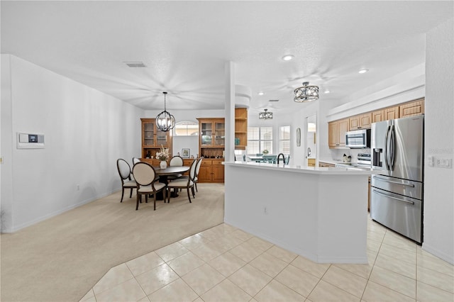 kitchen with light tile patterned flooring, light countertops, stainless steel appliances, light carpet, and an inviting chandelier