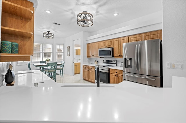 kitchen with light countertops, open shelves, appliances with stainless steel finishes, brown cabinets, and visible vents