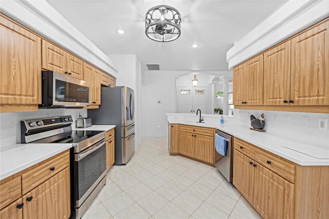 kitchen featuring decorative backsplash, a sink, visible vents, a peninsula, and appliances with stainless steel finishes