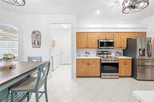kitchen with light tile patterned flooring, light countertops, recessed lighting, appliances with stainless steel finishes, and washer and dryer