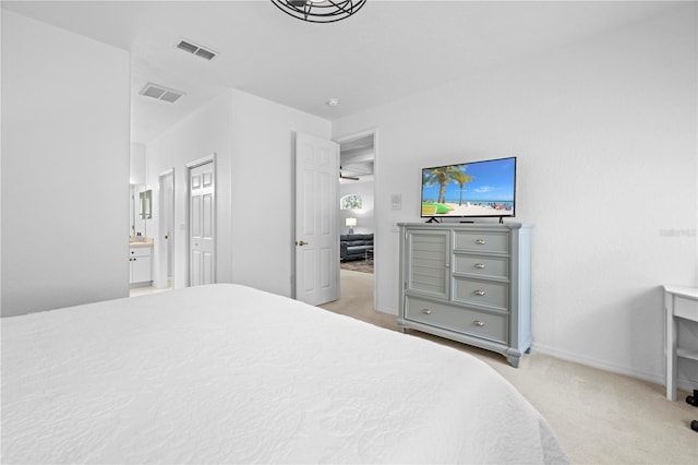 bedroom with baseboards, connected bathroom, visible vents, and light carpet