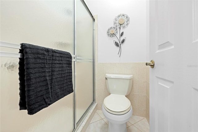 full bath featuring a stall shower, toilet, wainscoting, tile patterned flooring, and tile walls