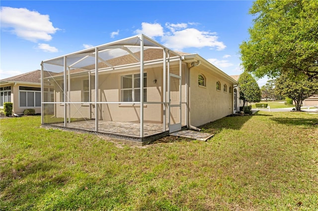 rear view of property with stucco siding, a lanai, a patio area, and a yard
